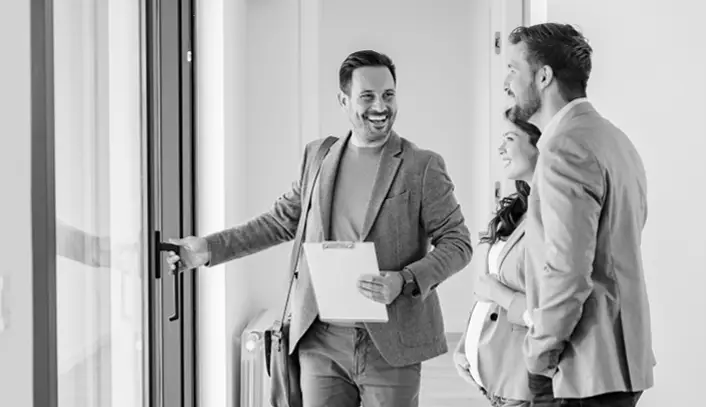 Smiling male accompanied by two co-workers exiting a building